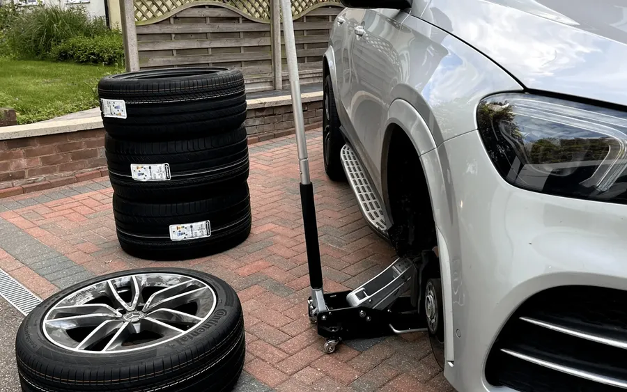 Mercedes SUV being jacked up by a QuickGrip technician with a stack of new tyres ready to fit